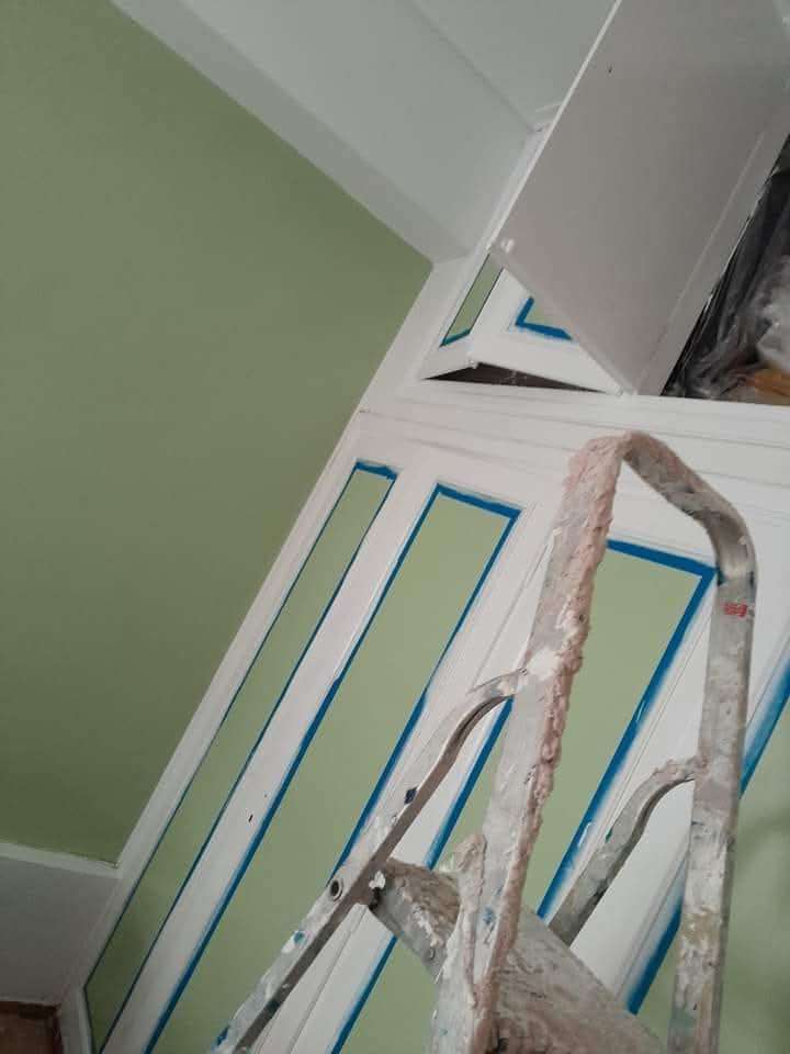 Interior room with green painted walls and doors, painter's ladder in view